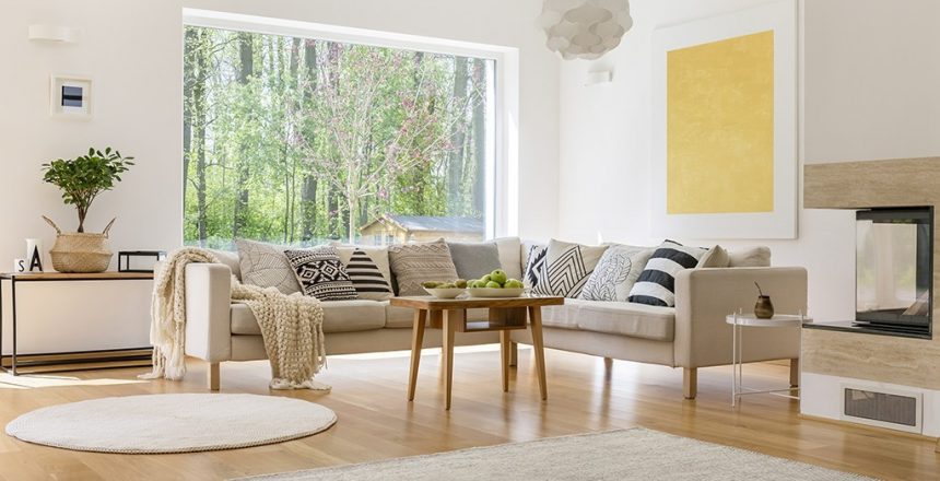 White comfortable sofa with blanket and pillows in modern lounge